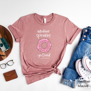 May include: A heather mauve t-shirt with a pink donut graphic and the text "whatever sprinkles ya donut".