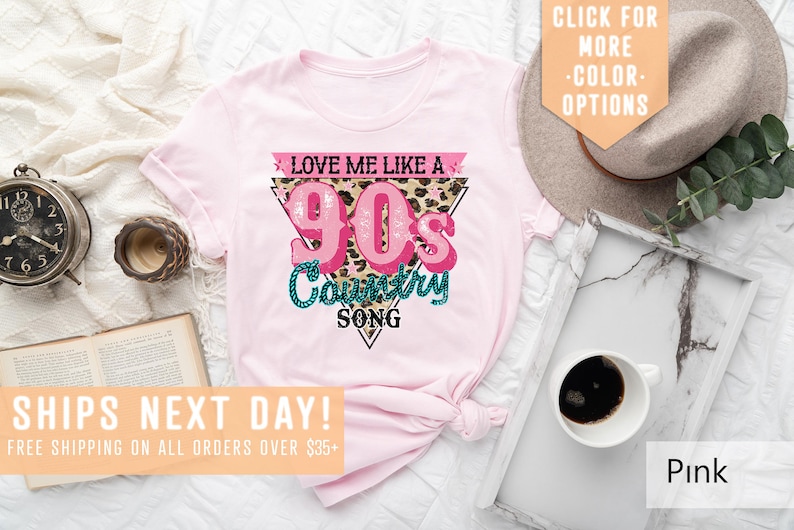 May include: Pink t-shirt featuring a graphic design that reads "Love Me Like A 90s Country Song" in a pink and teal colour scheme with a leopard print background.