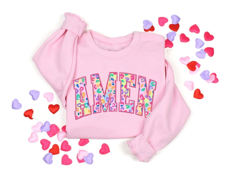 Puede incluir: Sudadera rosa con la palabra "AMEN" en letras de estampado de leopardo arco&iacute;ris.