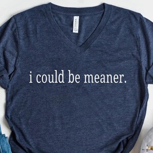 May include: Navy blue V-neck t-shirt with the text "i could be meaner" in white. The shirt is made of a soft material. The shirt is a casual wear item.