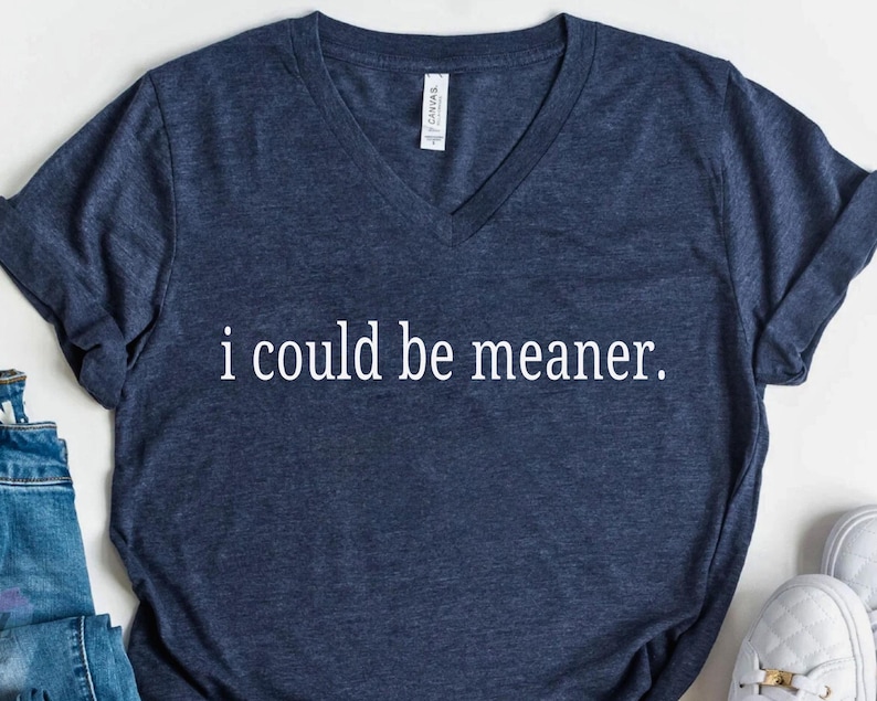 May include: Navy blue V-neck t-shirt with the text "i could be meaner" in white. The shirt is made of a soft material. The shirt is a casual wear item.