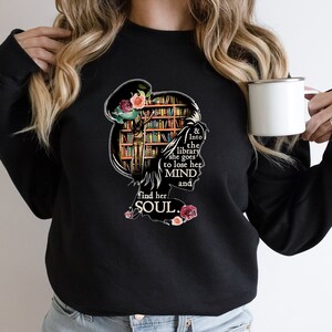 May include: Black sweatshirt with a graphic of a woman standing in a library with the text "& Into the library she goes to lose her MIND and find her SOUL."