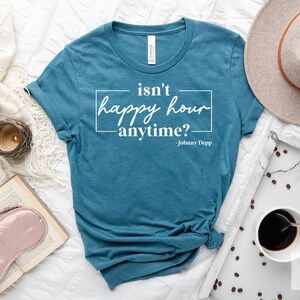 May include: A teal blue t-shirt with the text "isn't happy hour anytime? - Johnny Depp" printed in white.