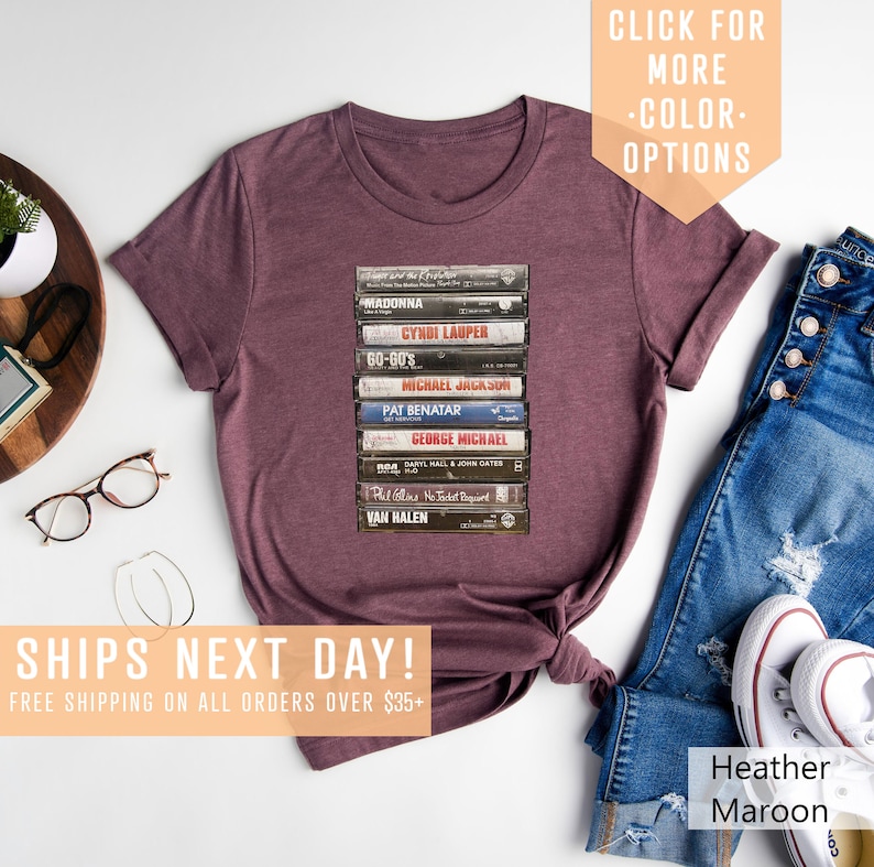 May include: A heather maroon t-shirt with a stack of vintage cassette tapes featuring artists like Madonna, Cyndi Lauper, and Van Halen. The text "SHIPS NEXT DAY! FREE SHIPPING ON ALL ORDERS OVER $35+" is printed below the image.