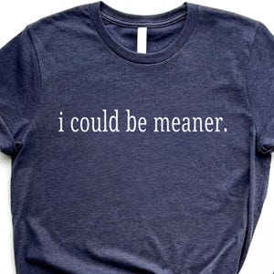 May include: Navy blue t-shirt with the white text "i could be meaner." The shirt has a crew neck and short sleeves. The fabric appears to be a soft, heathered material.