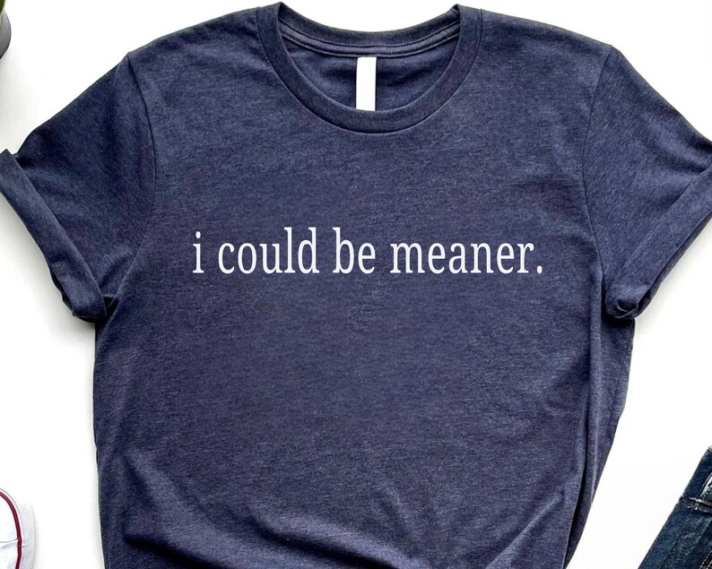 May include: Navy blue t-shirt with the white text "i could be meaner." The shirt has a crew neck and short sleeves. The fabric appears to be a soft, heathered material.