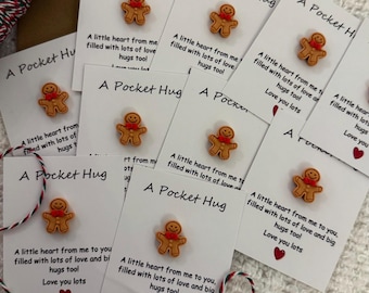 May include: A set of eight small white cards with a gingerbread man sticker on each. The cards have the text "A Pocket Hug" and a message about love and hugs.