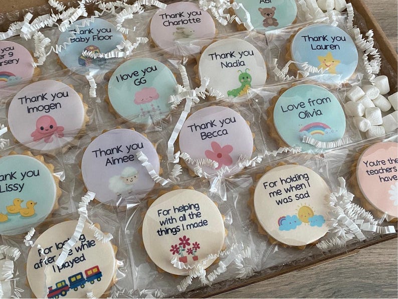 May include: A collection of round biscuits individually wrapped in clear plastic, each featuring a unique printed design with text such as Thank you Charlotte, Thank you Nadia, Love from Olivia, and For helping with all the things I made.