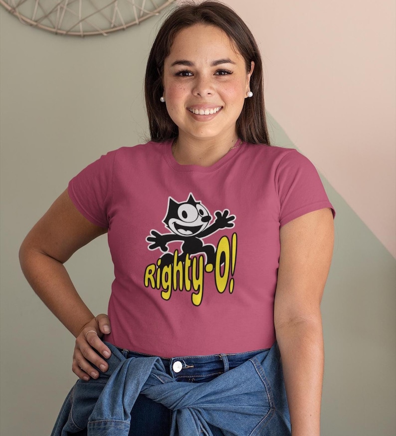 May include: A pink t-shirt with a black and white cartoon cat wearing a yellow hat and the text "Righty-O!" in yellow.