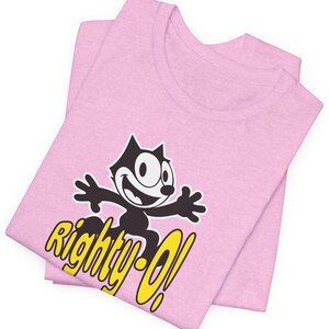May include: Pink t-shirt with a black and white cartoon cat wearing a yellow hat and the text "Righty-O!" in yellow.