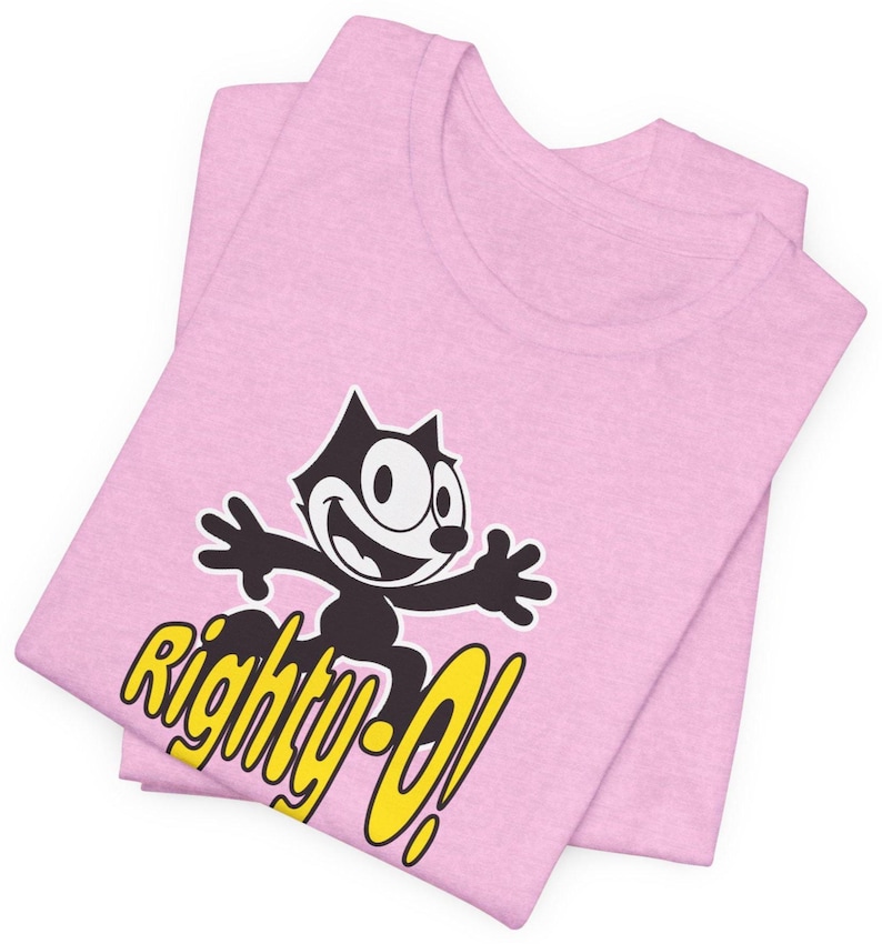 May include: Pink t-shirt with a black and white cartoon cat wearing a yellow hat and the text "Righty-O!" in yellow.