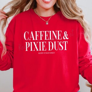May include: Red sweatshirt with white text that reads "Caffeine & Pixie Dust Keepin' It Mainstreet".