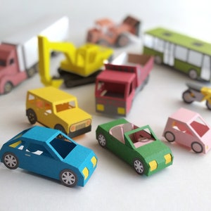 May include: A collection of colorful paper toy vehicles, including a blue car, green convertible, pink car, yellow jeep, red truck, and a yellow excavator. Other vehicles include a bus, motorcycle, and a semi-truck.