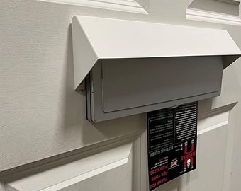 Capot de sécurité pour boîte aux lettres. Il suffit de visser pour s'adapter aux portes en bois et en PVC. Finition blanc mat, empêche la pêche à la clé et l'inspection visuelle.