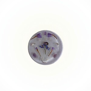 Peut inclure: Un dessous de verre rond en résine transparente avec une fleur violette et des cristaux d'améthyste incrustés. Le dessous de verre a un motif de croissant de lune argenté.