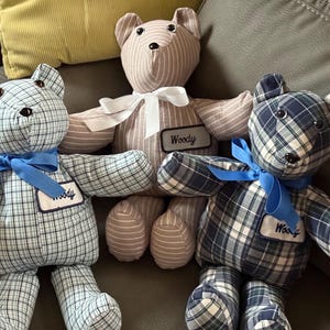 May include: Three handmade teddy bears in a row. The bears have different patterns: blue and white plaid, tan and white stripes, and dark blue and white plaid. Each bear has a bow and a name tag that says "Woody".