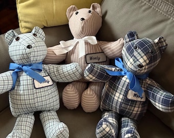 Pode incluir: Três ursos de pelúcia feitos à mão. Um é listrado, os outros são xadrez. Cada urso tem um laço e uma etiqueta com o nome "Woody". Os ursos são em tons de azul, bege e branco. Um presente charmoso e artesanal.