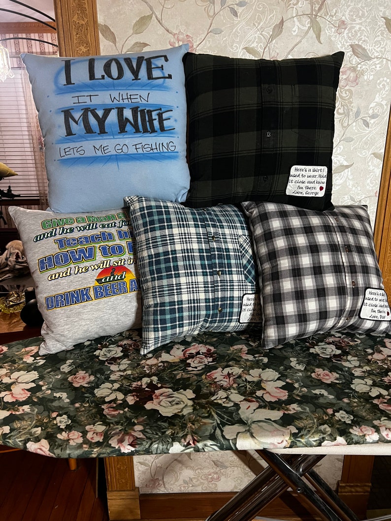 May include: Four decorative pillows with different designs. One pillow is blue with the text "I love it when my wife lets me go fishing". Another pillow is gray with the text "Give a man a beer and he will earn for you, teach him how to fish and he will sit up and drink beer all day". The other two pillows are made from plaid fabric.