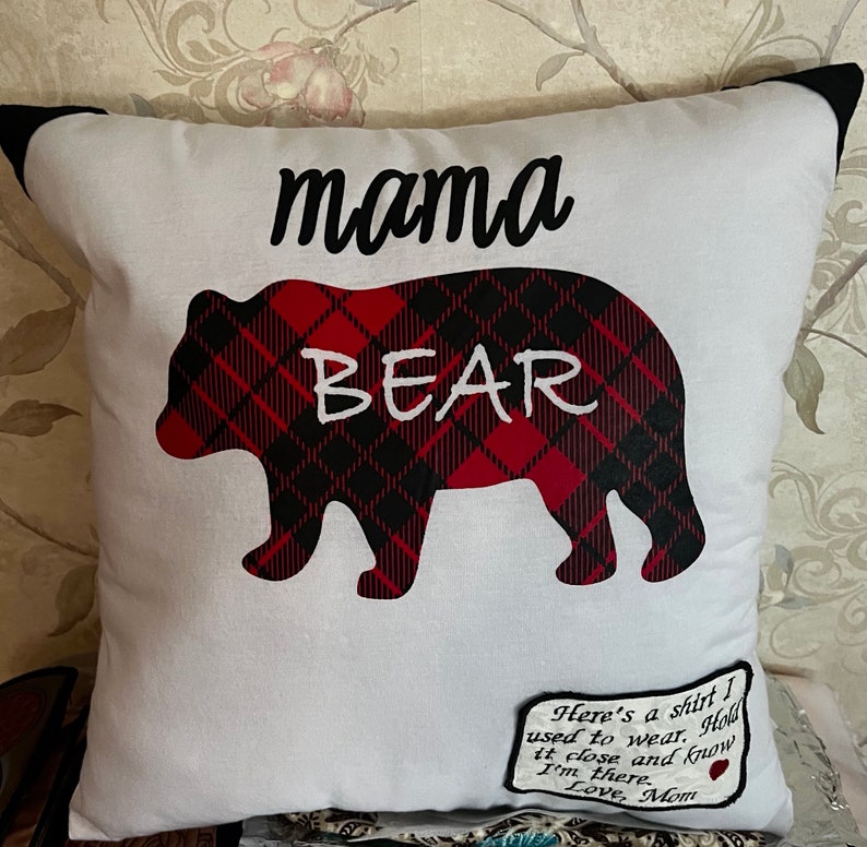 May include: White pillow with a black and red plaid bear silhouette and the text "mama bear". A small tag attached to the pillow reads "Here's a shirt I used to wear. Hold it close and know I'm there. Love, Mom."