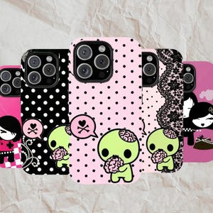 May include: A collection of phone cases with unique designs. The cases feature various patterns, including polka dots and lace, and showcase cartoon characters with brains and skull-and-crossbones speech bubbles. The color palette includes pink, black, and white.