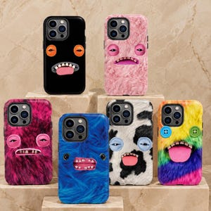 May include: Six smartphone cases featuring various textures and monster-like faces. One is smooth black, while the others are covered in faux fur in pink, magenta, blue, black and white cow print, and a rainbow pattern with button eyes.