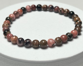 May include: A pink, brown, and black gemstone bracelet with round beads.