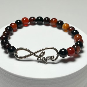 May include: A bracelet with black, red, and brown beads and an infinity symbol charm with the word "Hope" inscribed on it.