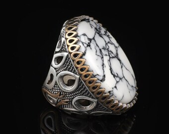 May include: A silver ring with a white and black marbled stone set in a detailed silver and gold design.