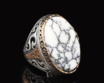 May include: A silver ring with a white oval-shaped stone set in a gold-toned filigree design.