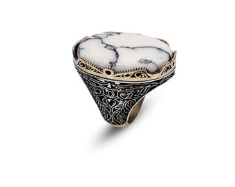 May include: A silver ring with a white oval stone set in a gold filigree design.
