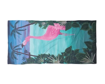 Op de afbeelding: Een rechthoekige strandhanddoek met een felroze flamingo in het midden tegen een tropische achtergrond. De scène bevat een blauwe oceaan, een zonsonderganglucht, silhouetten van palmbomen links en donkergroen gebladerte aan de rechterkant.