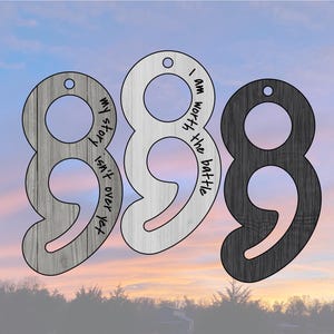 May include: Three semicolon-shaped wooden ornaments in grey, white, and black. Each has a hole for hanging and a different inspirational quote: "my story isn't over yet," and "I am worth the battle."
