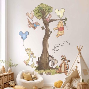 May include: A wall decal featuring Winnie the Pooh characters including Pooh, Piglet, Tigger, Eeyore, Rabbit, and Roo gathered around a large tree. The characters are holding Mickey Mouse-shaped balloons in light blue, pink, and yellow colours.