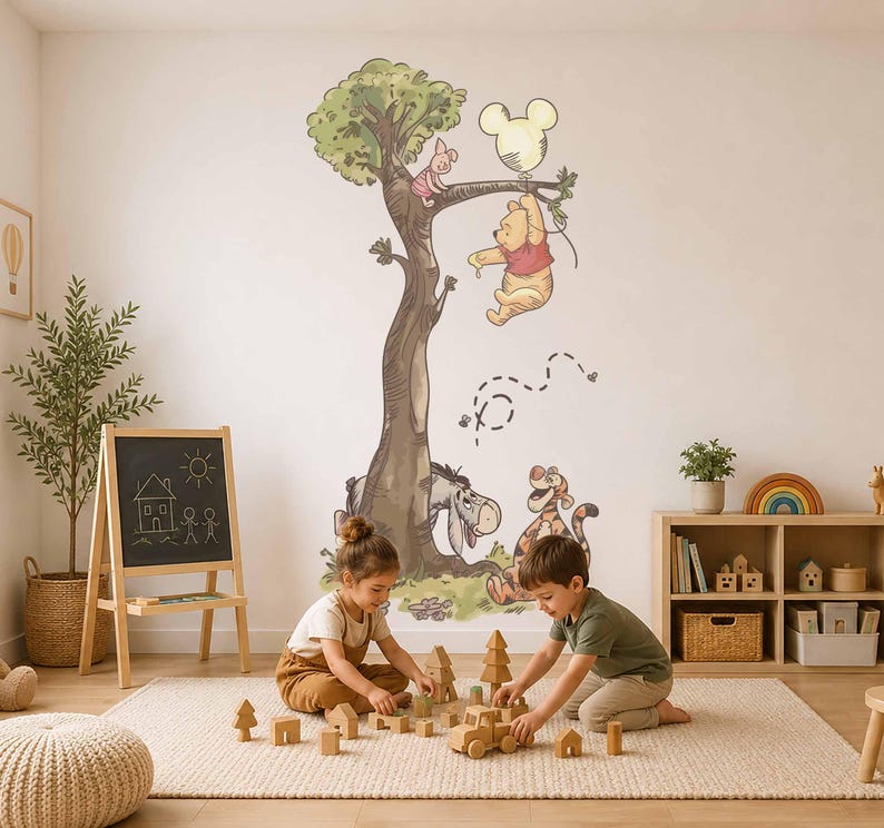 May include: A wall decal featuring a large tree with Winnie the Pooh hanging from a branch by a Mickey Mouse-shaped balloon, Piglet sitting on a branch, and Eeyore and Tigger resting at the base of the tree trunk, all rendered in a soft illustration style.