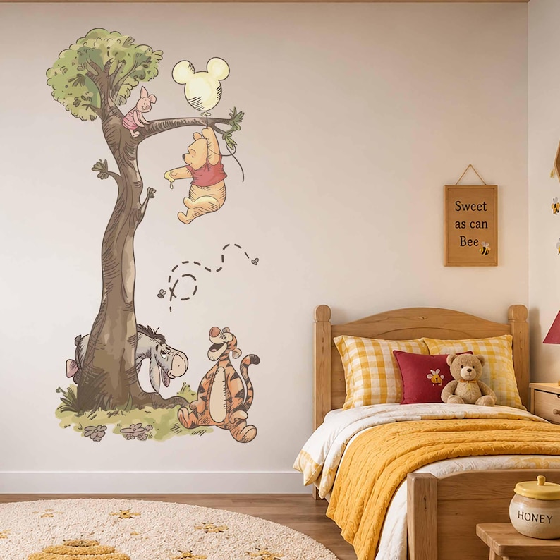 May include: A wall decal featuring Winnie the Pooh, Piglet, Eeyore, and Tigger around a tree. Pooh holds a Mickey Mouse-shaped balloon. A wooden sign on the wall reads Sweet as can Bee. The characters are illustrated in a soft, watercolour style.