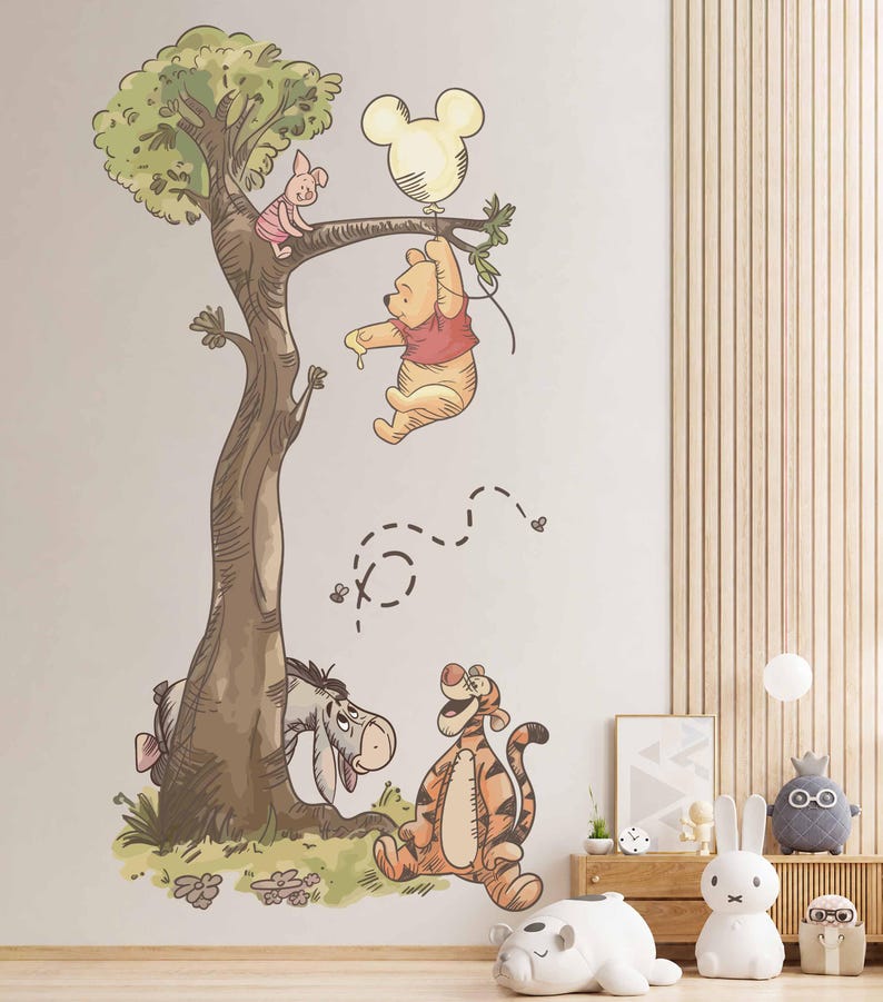 May include: A wall decal featuring Winnie the Pooh hanging from a tree branch while holding a Mickey Mouse-shaped balloon, with Piglet sitting on a branch above, and Eeyore and Tigger standing at the base of the tree with small bees flying nearby.