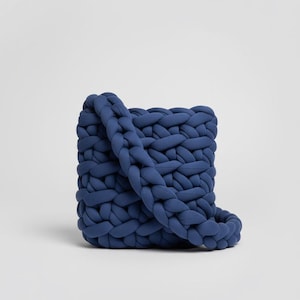 Peut inclure: Sac à bandoulière bleu marine tricoté à la main. Le sac est de forme carrée avec une épaisse bandoulière tressée. La construction en tricot épais donne au sac un aspect texturé. Le sac est fait d'un matériau doux et souple.