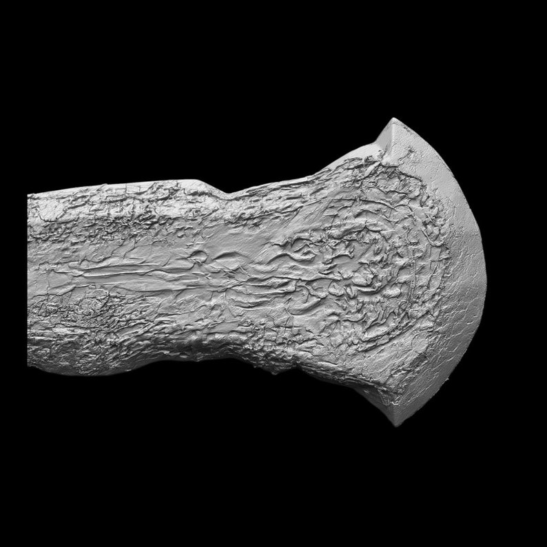 May include: A silver-coloured axe head with a textured surface. The axe head is shaped like a crescent moon.