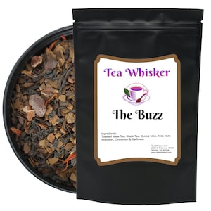 May include: A black resealable pouch with a label that reads "Tea Whisker The Buzz". The label has a brown background and a white border. The ingredients are listed on the label: Toasted Mate Tea, Black Tea, Cocoa Nibs, Kola Nuts Inclusion, Cinnamon & Safflower. The pouch contains loose leaf tea.