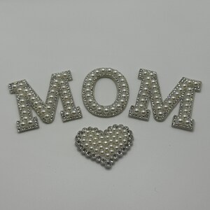 May include: White pearl MOM letters with a white pearl heart.