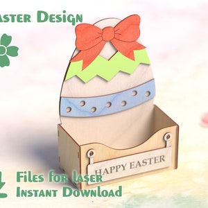 May include: A wooden Easter egg-shaped box with a red bow and the words "Happy Easter" on the front. The box is decorated with blue and green stripes and dots.