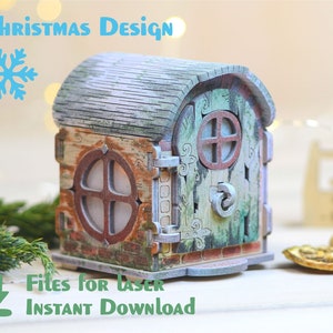 May include: A wooden Christmas house with a green and brown roof, a brown door with a window, and a brown window on the side. The house is sitting on a white surface. The text "Files for Laser Instant Download" is at the bottom of the image.