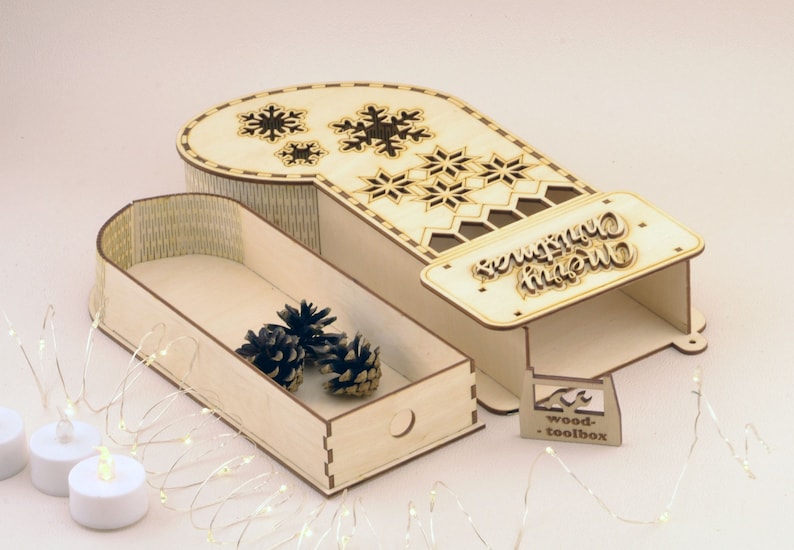 May include: A wooden Christmas stocking box with a drawer and a cutout design of snowflakes. The box has a sign that says "Merry Christmas".