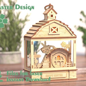 Puede incluir: Una casa de Pascua de madera cortada con láser con un conejito tirando de un carro, una gallina y un cartel que dice "conejos". La casa tiene una ventana con una luz en el interior y el texto "Feliz Pascua" en la parte inferior.