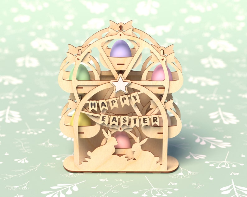 May include: Wooden Easter egg holder shaped like a Ferris wheel with the words "Happy Easter" on the front. The holder has five compartments for eggs and two bunny rabbits at the bottom.