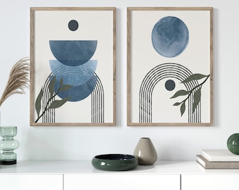 May include: Two framed abstract art prints featuring blue and white geometric shapes and green leaves. The prints are in wooden frames and are hanging on a white wall.