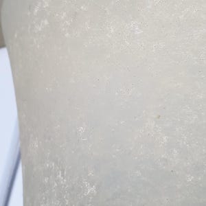 May include: Close-up of a textured, off-white, cylindrical object. The surface has a mottled appearance with small, dark spots. The object's shape suggests it could be a part of a larger structure or a decorative item.