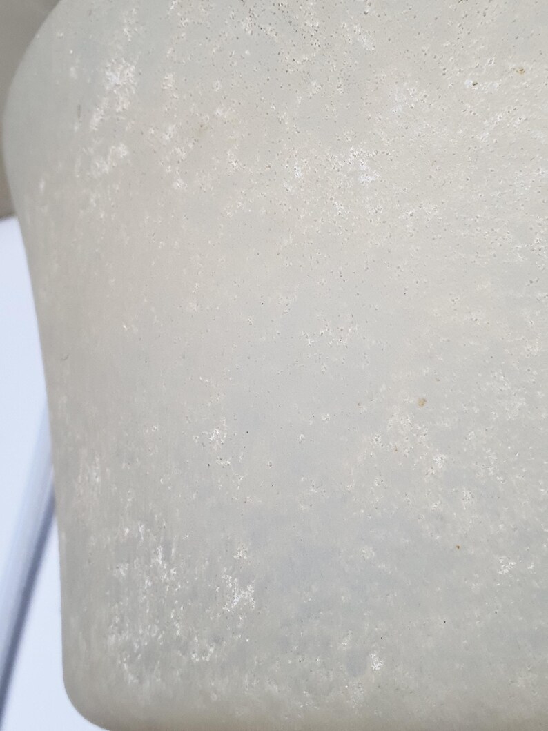 May include: Close-up of a textured, off-white, cylindrical object. The surface has a mottled appearance with small, dark spots. The object's shape suggests it could be a part of a larger structure or a decorative item.