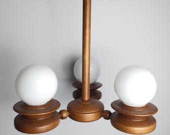 May include: A ceiling light fitting featuring a central wooden stem and three horizontal wooden arms. Each arm supports a circular wooden base topped with a spherical white glass globe. The wood has a smooth, medium-brown finish throughout.