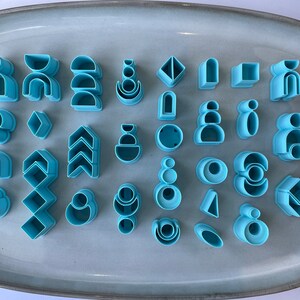 Puede incluir: Un conjunto de 30 cortadores de galletas de pl&aacute;stico azul en varias formas geom&eacute;tricas, incluyendo c&iacute;rculos, cuadrados, tri&aacute;ngulos y arcos.